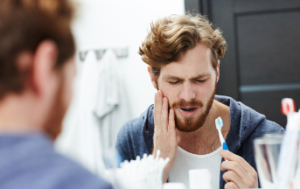 man holding toothbrush with tooth pain