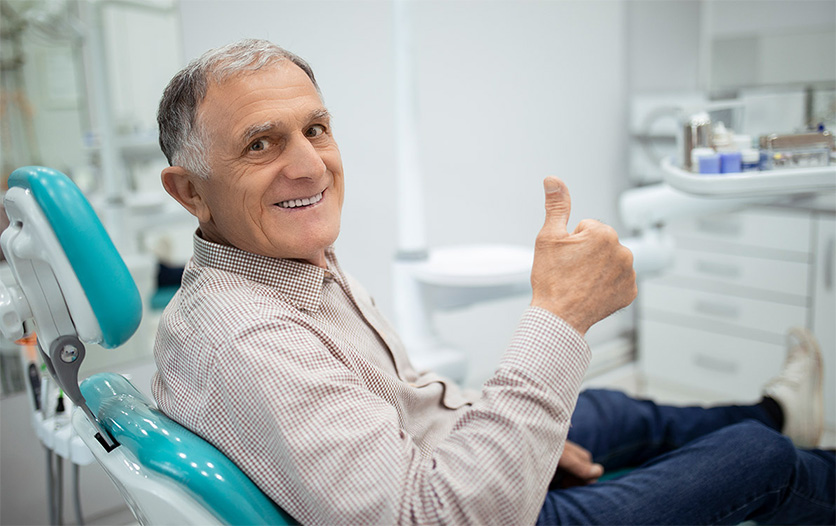 Elderly gentleman giving thumbs up in dental chair