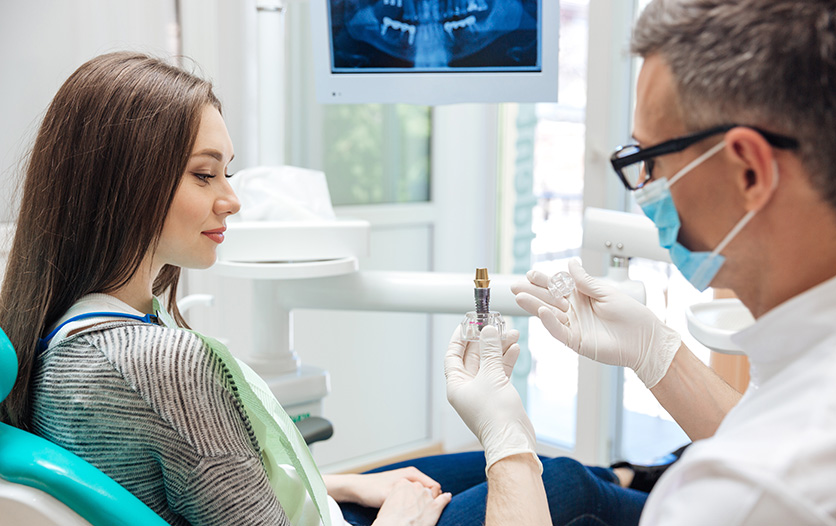 dentist explaining dental implant model to patient