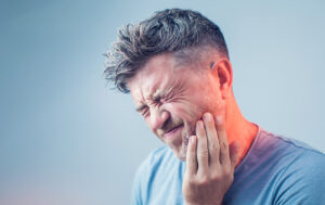 Man with toothache holding jawline